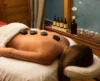 A woman relaxing for a massage with warm stones on her back.