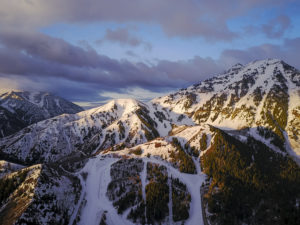 The sun sets over white snowy mountain peaks near Park City, Utah.