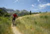 A man mountain bikes through a lush green valley at the resort.