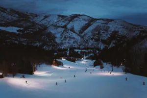 Evening view of the mountainside and many people out night skiing.