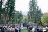 An outdoor Utah wedding ceremony taking place in a forest setting with tall trees and mountain backdrop, attended by guests seated in rows and a couple standing at the altar.