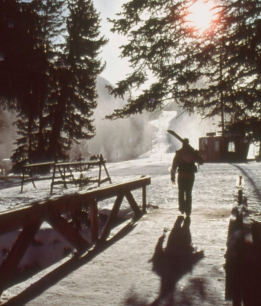  A vintage photo of a skiier walking across a wooden bridge at Sundance Resort.