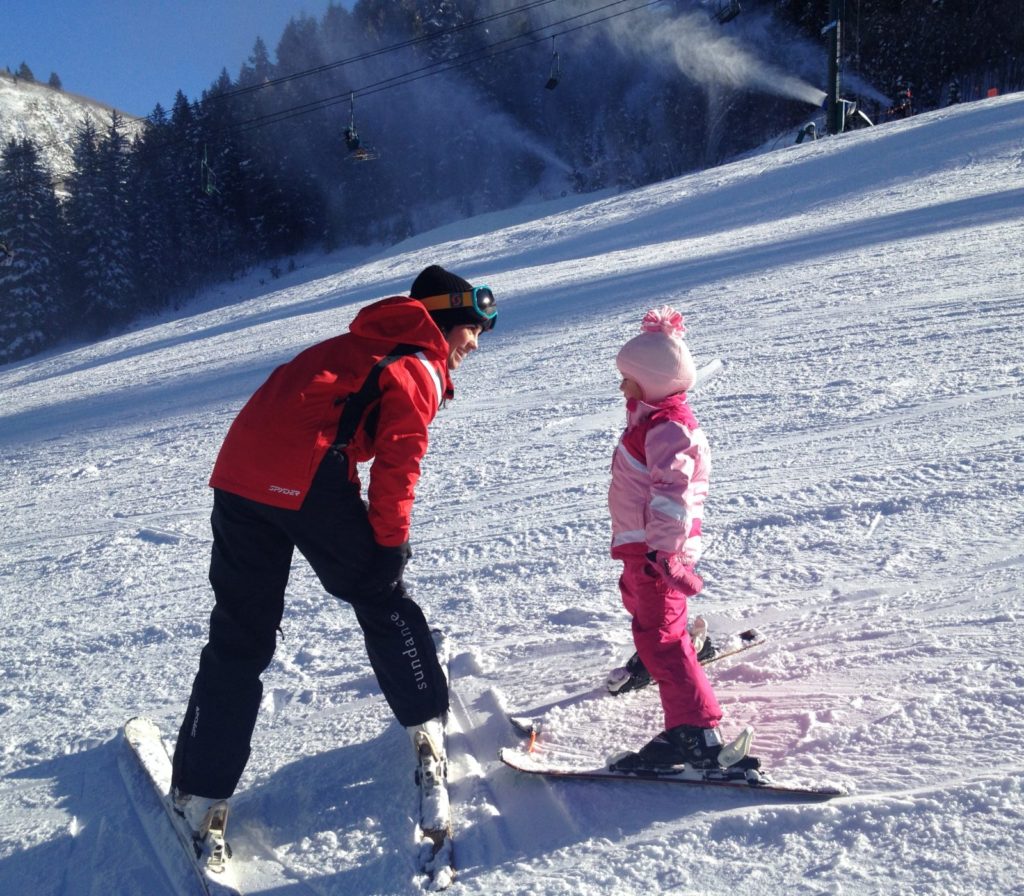 ski instructor with young girl on the snowy slope
