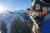 A woman on the ski lift looking out over the snow covered mountains on a sunny winter day.