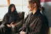 Two women smiling and relaxing in a spa setting, one blurred in the background, both wearing brown robes. comfortable and cozy ambiance with soft lighting.
