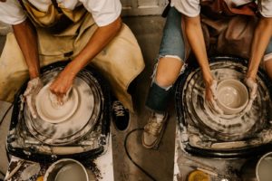 Two individuals shaping bowls on potters wheels.