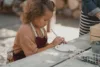 A young girl preparing her paints at the picnic table.