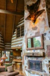 An exquisite stone fireplace rests next to windows overlooking the main floor of the Cascade Ridge home.