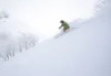 An individual skis down the mountain covered in fresh powder.