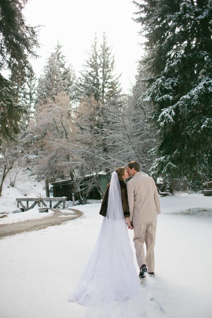 Newly married couple walking through the snow covered forest at Sundance Resort.