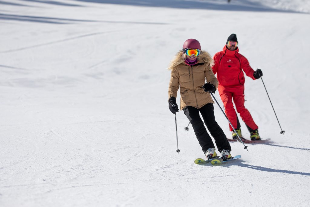 Woman skiing down the mountain at Sundance Resort with a ski instructor following behind. 