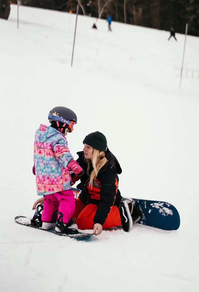 A Sundance Resort instructor teaches a young girl how to snowboard.