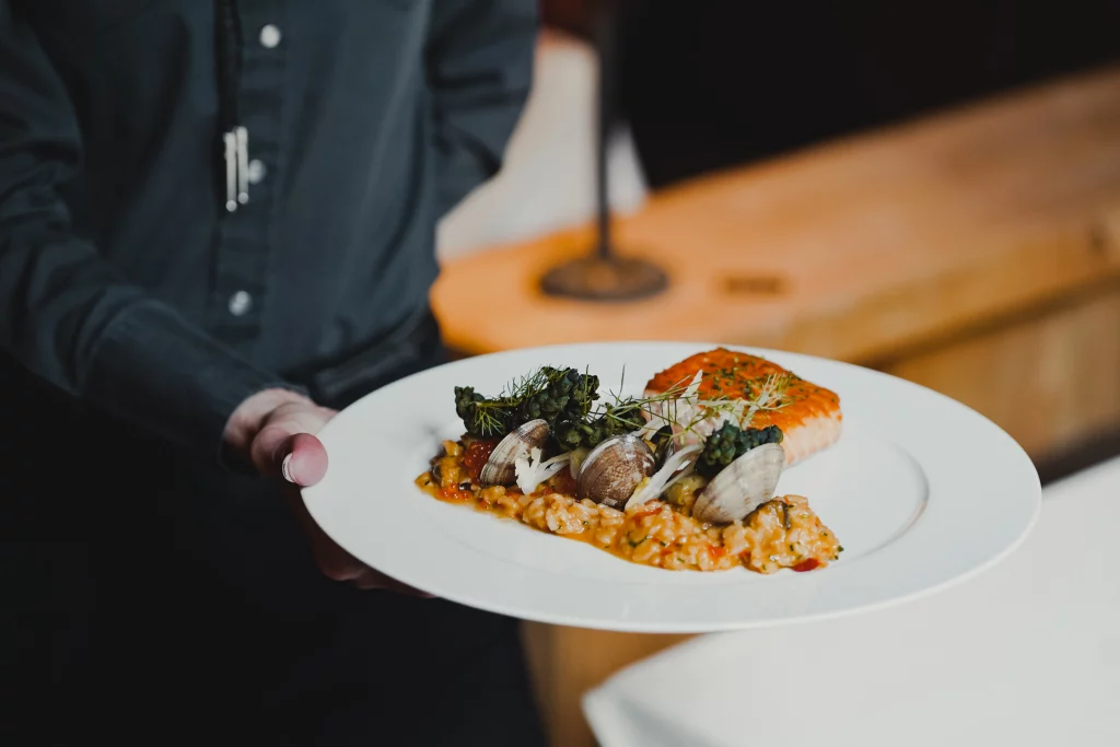 Waiter holding a beautifully plated dinner dish.