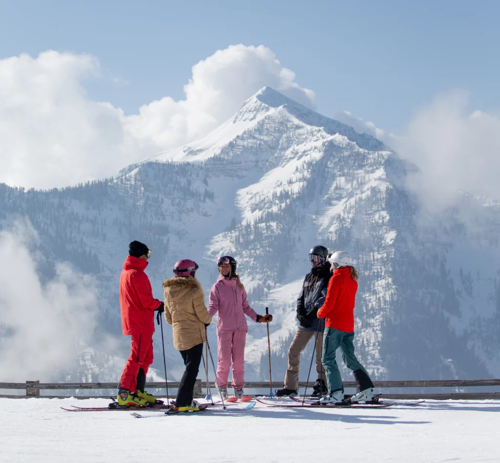 Five skiers enjoy the breathtaking views and good company at the top of the mountain.