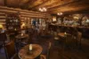 A cozy, rustic bar interior with wooden beams, vintage furnishings, and a well-stocked bar counter. the warm lighting and historic decor create an inviting atmosphere.
