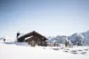 A cozy wooden ski lodge surrounded by skis and snowboards, nestled against a backdrop of snowy mountains under a clear blue sky. skiers gather nearby, enjoying the winter scenery.