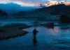 An individual fly fishing in the Provo River as the sun rises.