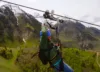 A man traveling down a zipline with a beautiful scenic view.