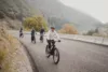 A happy group of bikers traveling up a paved road with beautiful mountain views.