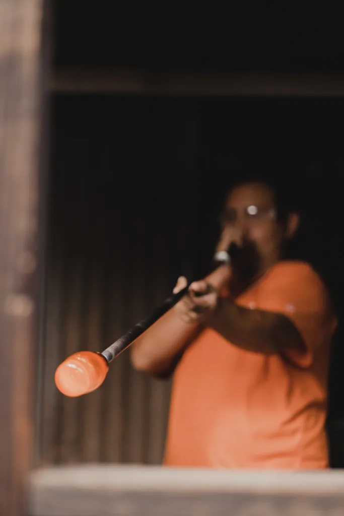 Artist in the process of blowing recycled glass to create a masterpiece. 