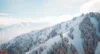 Beautiful clear day looking out over the top of snow covered mountains dotted with trees.