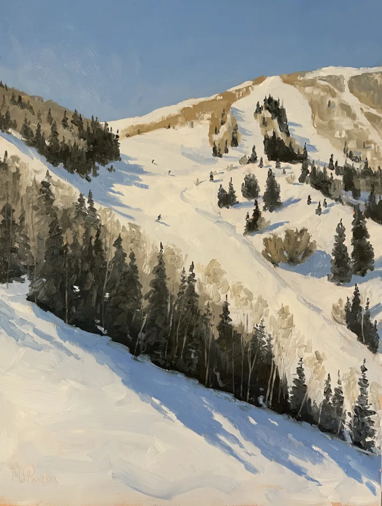 A snow-covered mountain slope dotted with pine trees under a clear blue sky. Ski tracks wind through the snow, with a few skiers visible in the distance descending the hill.