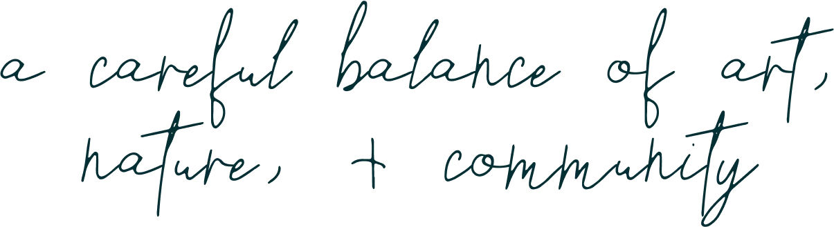 Handwritten text reads: "a careful balance of art, nature, + community" on a transparent background.